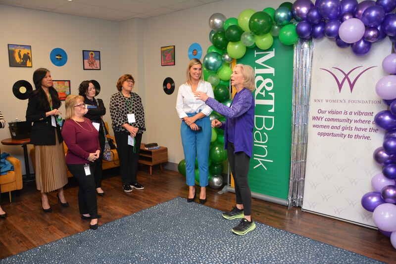 A group of women are standing in a room with balloons.
