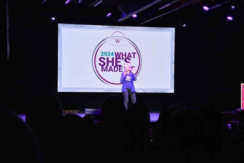 A woman is standing on a stage in front of a large screen that says `` what she made ''.