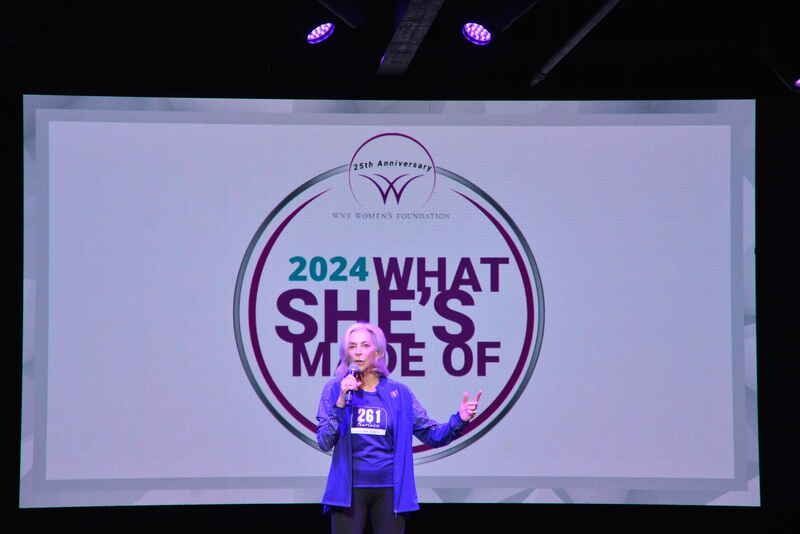 A woman is standing in front of a screen that says 2024 what she 's made of.