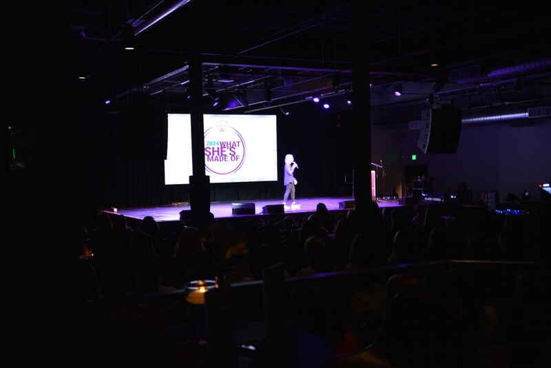 A woman is standing on a stage in front of a crowd.