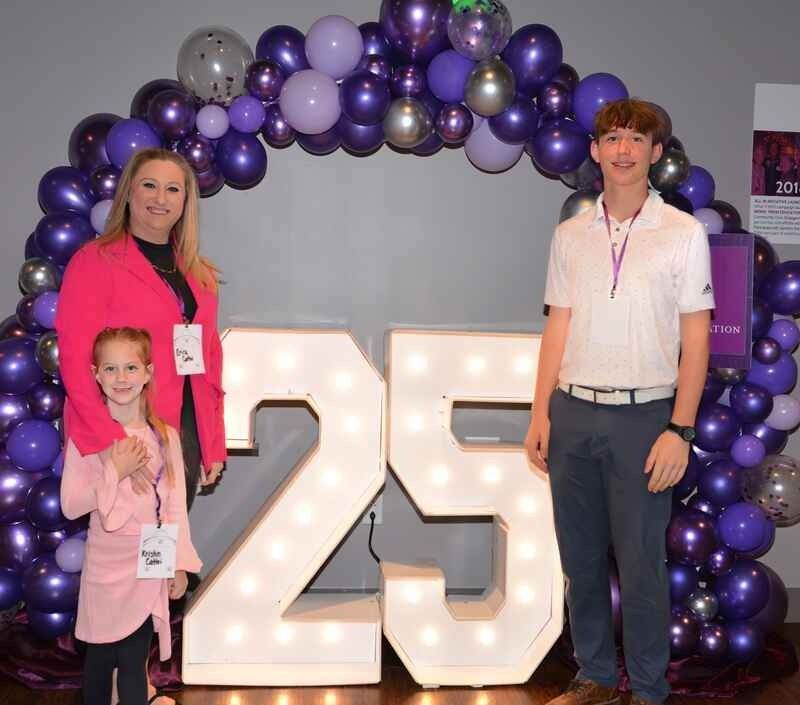 A group of people standing in front of a sign that says 25