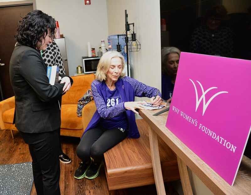 A woman is sitting on a bench next to a sign that says women 's foundation