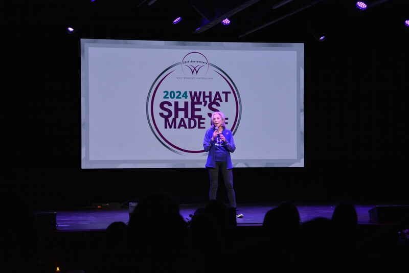 A woman is standing on a stage in front of a screen that says `` what she 's made ''.