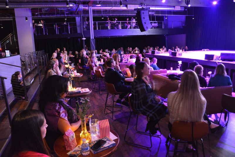A group of people are sitting in a theatre watching a show.