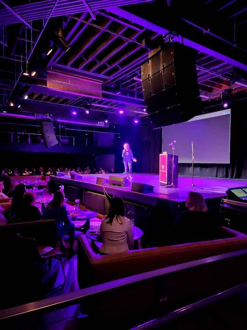 A man is standing on a stage in front of a crowd of people.