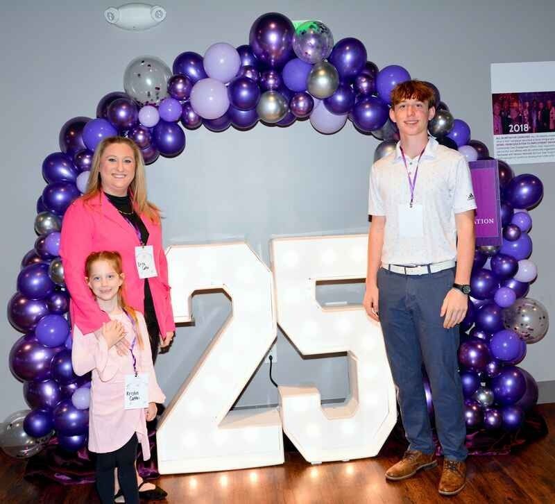 A group of people standing in front of a large number 25