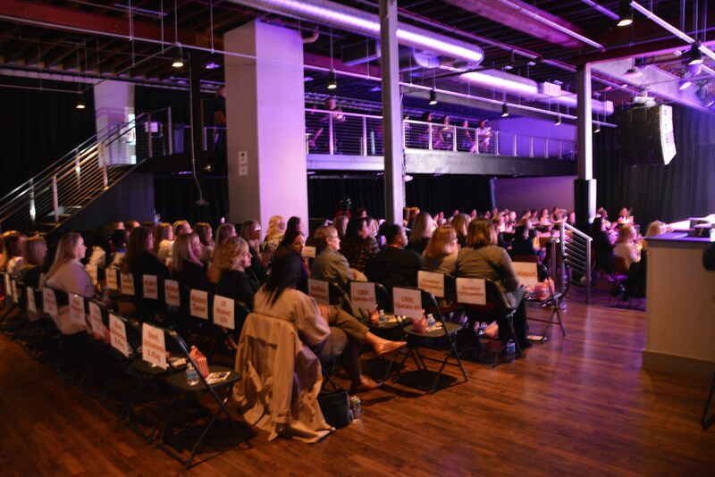 A large group of people are sitting in chairs in a large room.