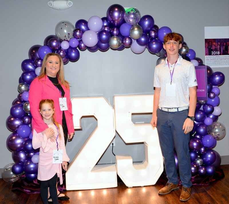 A group of people standing in front of a sign that says 25
