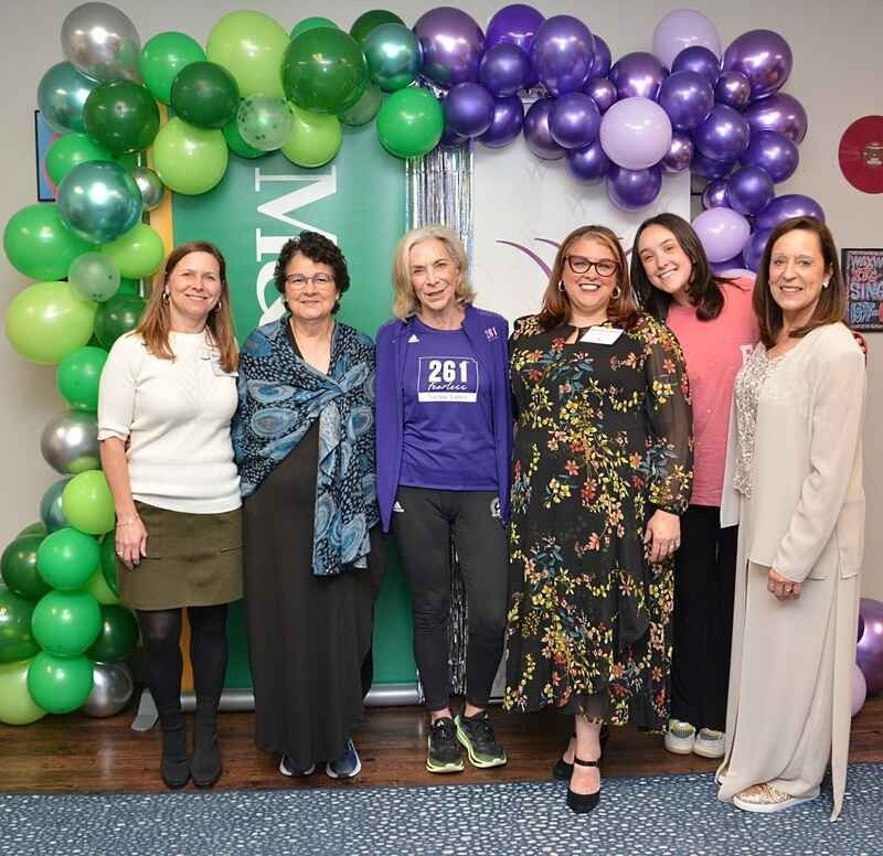 A group of women are posing for a picture with balloons in the background