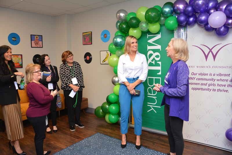 A group of women are standing in a room with balloons.
