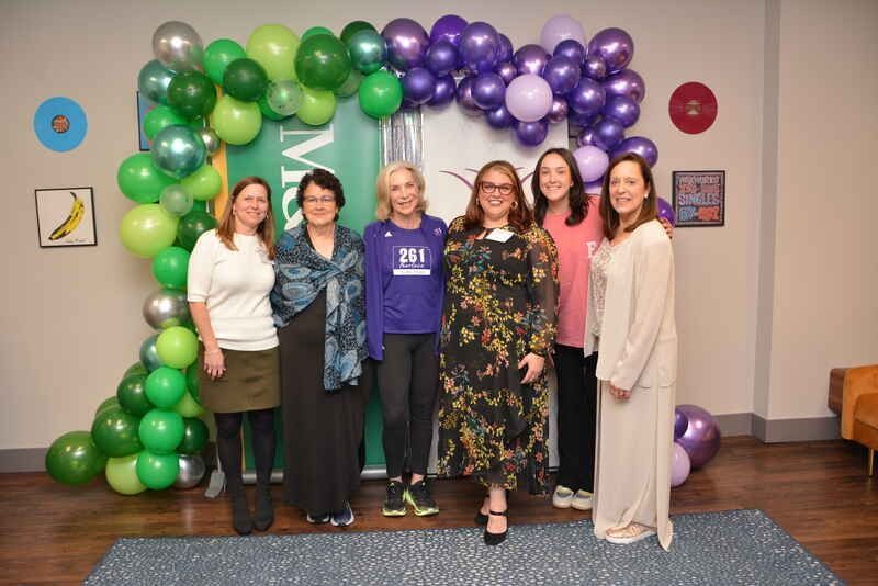 A group of women are posing for a picture in front of balloons.