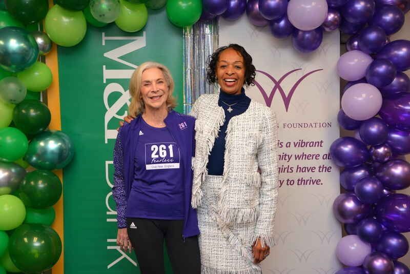 Two women are posing for a picture in front of balloons.