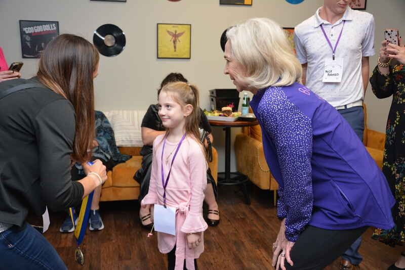 A woman is taking a picture of a little girl in a pink dress.