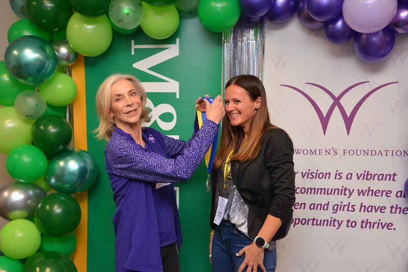 Two women are standing next to each other in front of balloons.