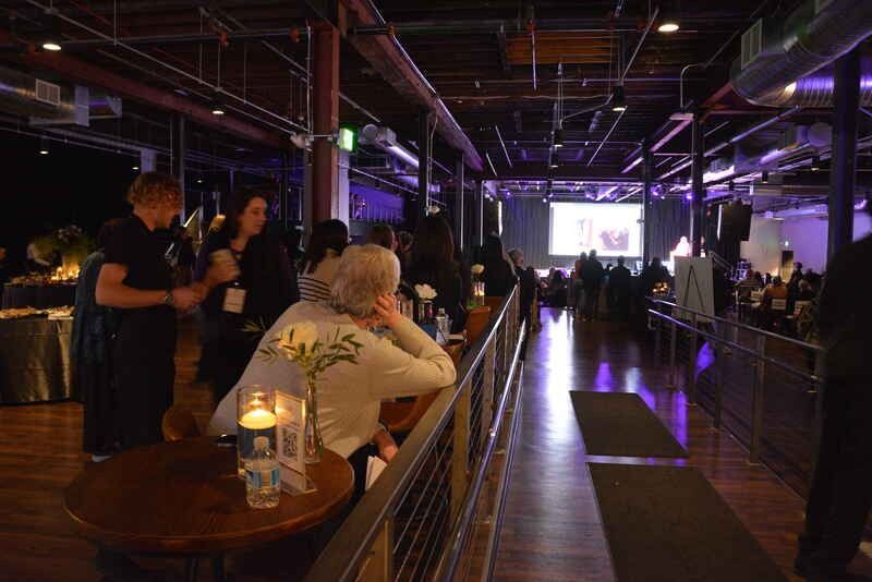 A group of people are sitting at tables in a large room.