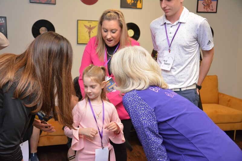A group of people are standing around a little girl in a room.
