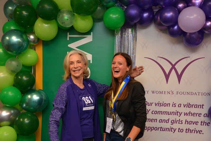 Two women are posing for a picture in front of balloons.