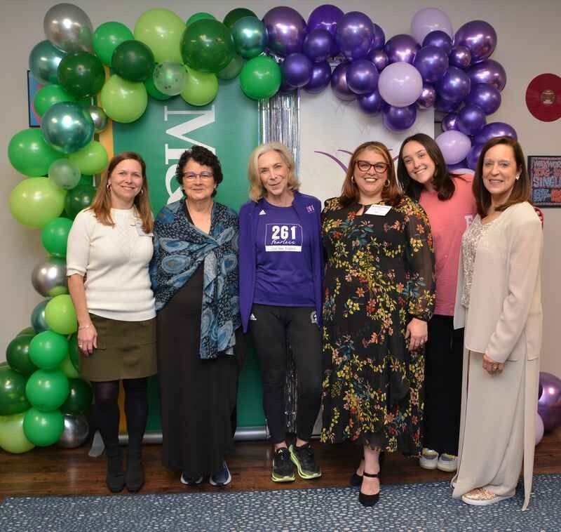 A group of women standing in front of balloons with one wearing a shirt that says 261