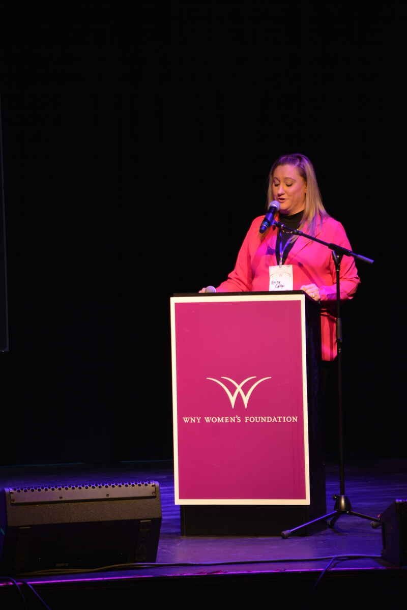 A woman is standing at a podium speaking into a microphone.
