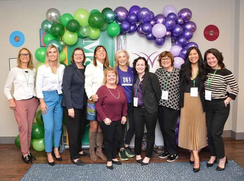 A group of women are posing for a picture in front of balloons.