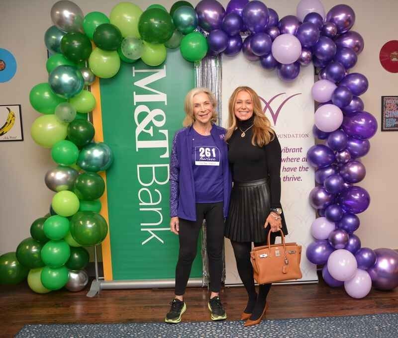 Two women standing in front of a misfit bank banner