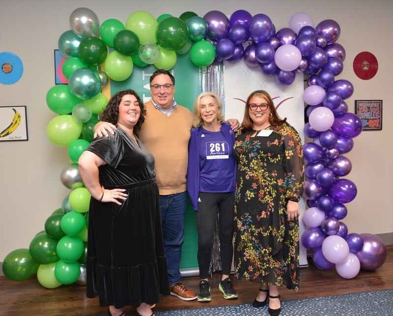 A group of people are posing for a picture in front of a balloon arch.