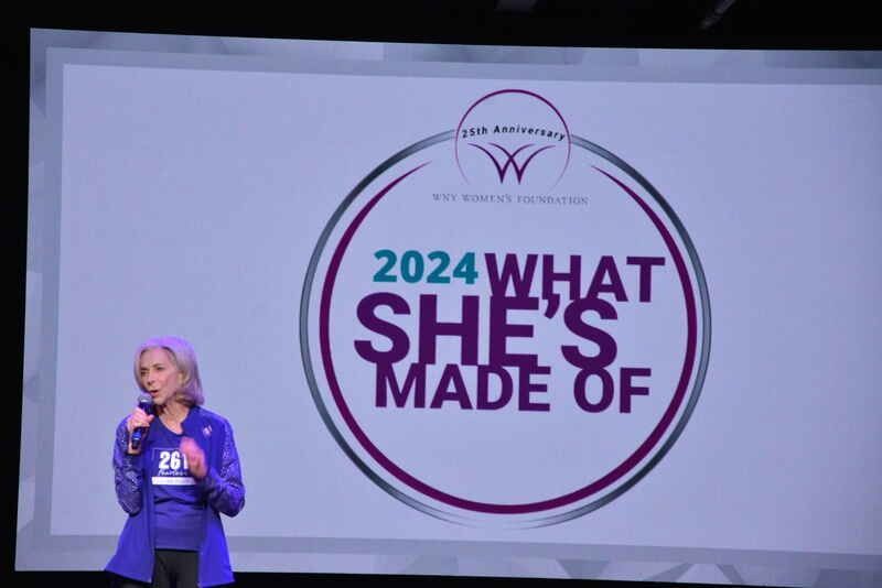 A woman stands in front of a screen that says 2024 what she 's made of