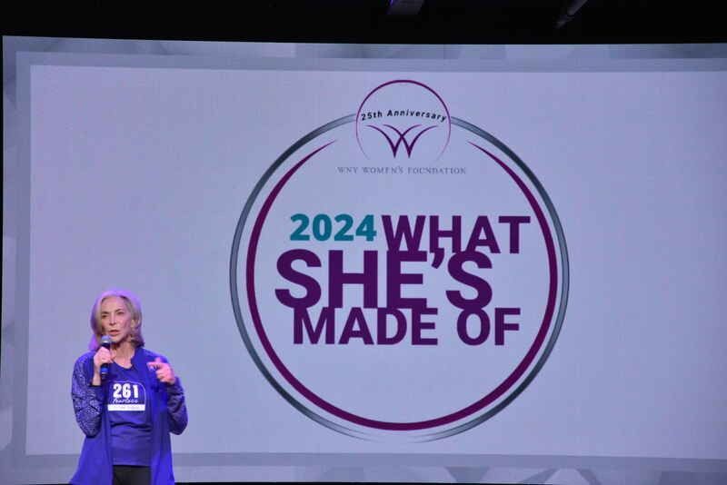 A woman stands in front of a screen that says 2024 what she 's made of
