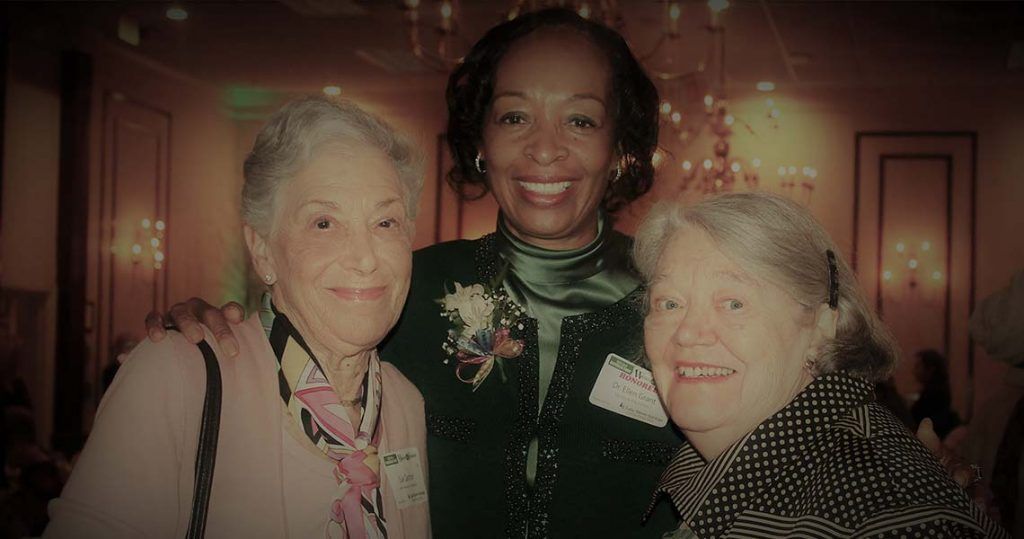 Three older women are posing for a picture together in a room.