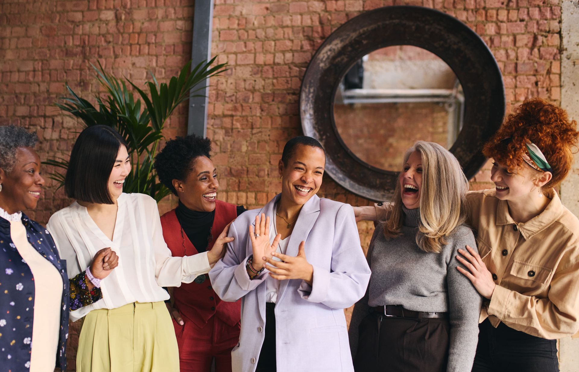 A group of women are standing next to each other in front of a brick wall.
