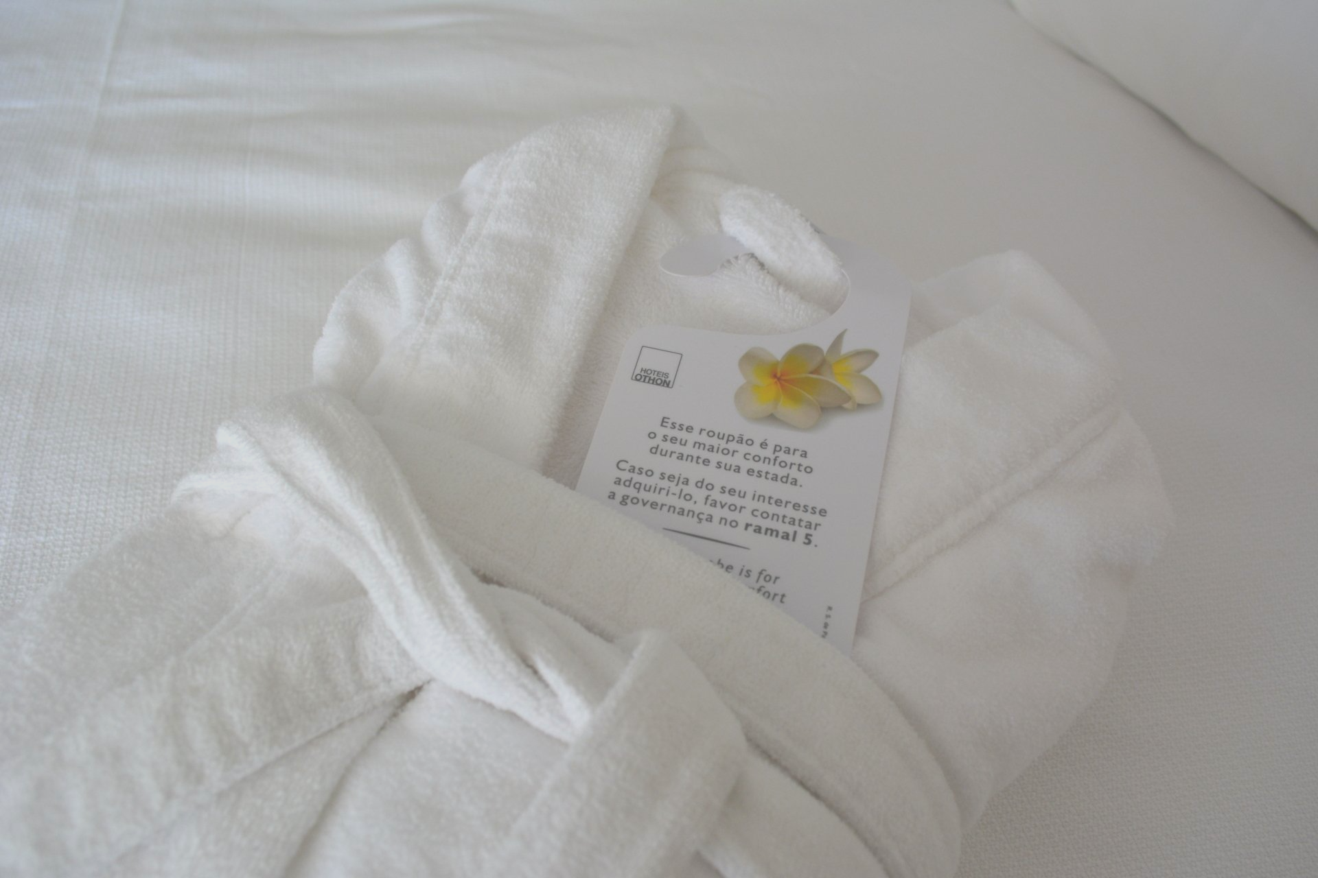 Um manto branco está deitado em uma cama ao lado de uma nota