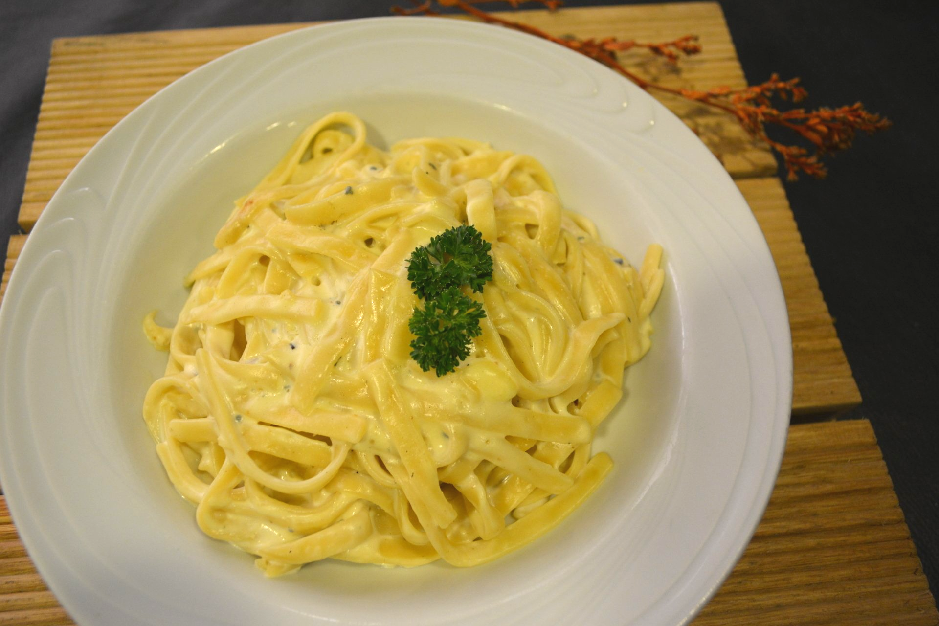 Um prato branco coberto com macarrão e queijo sobre uma mesa de madeira.