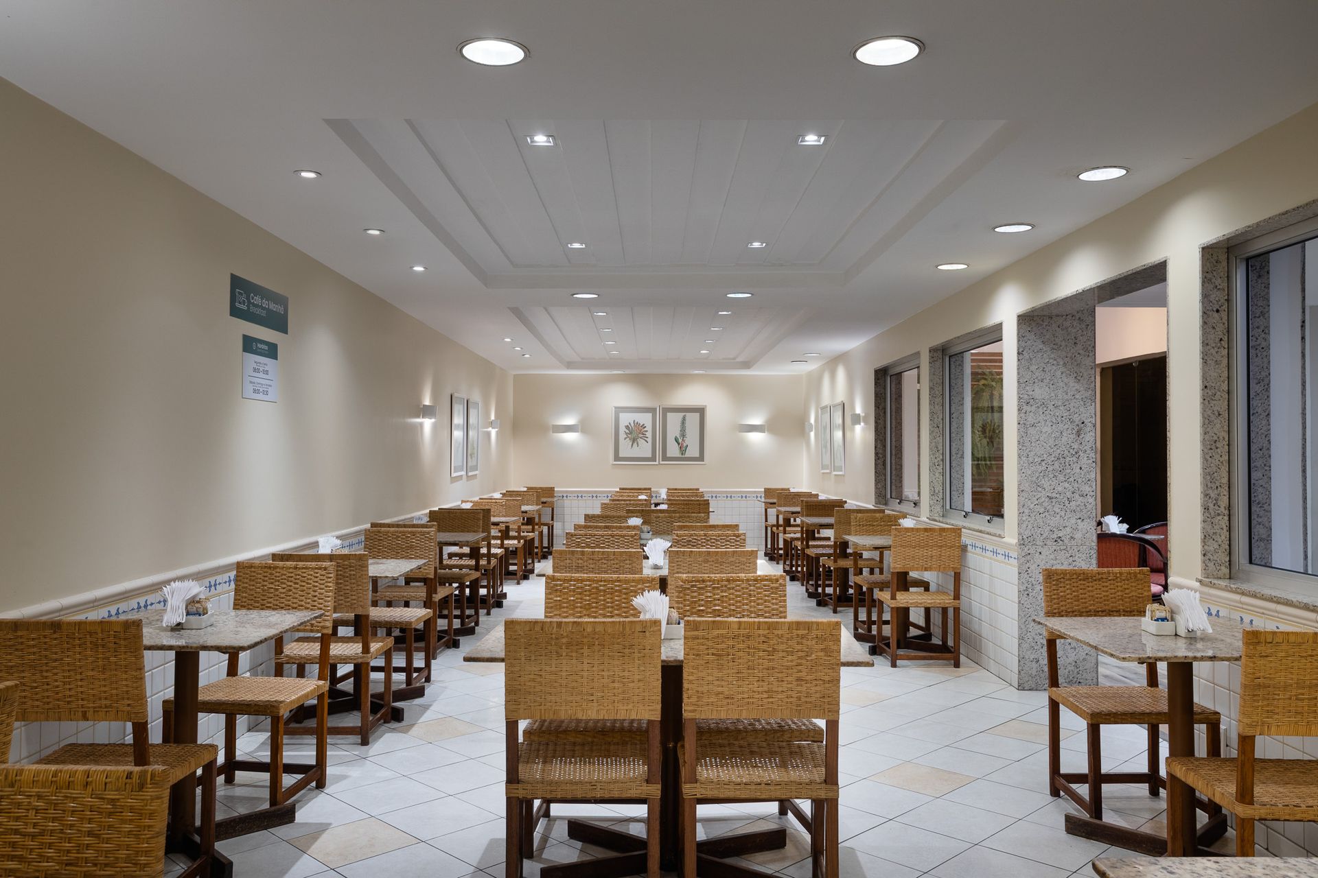 Um restaurante com mesas e cadeiras e uma televisão na parede.