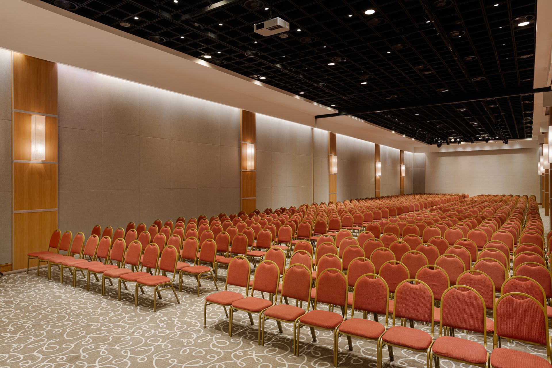 Um grande auditório cheio de cadeiras vermelhas e um projetor