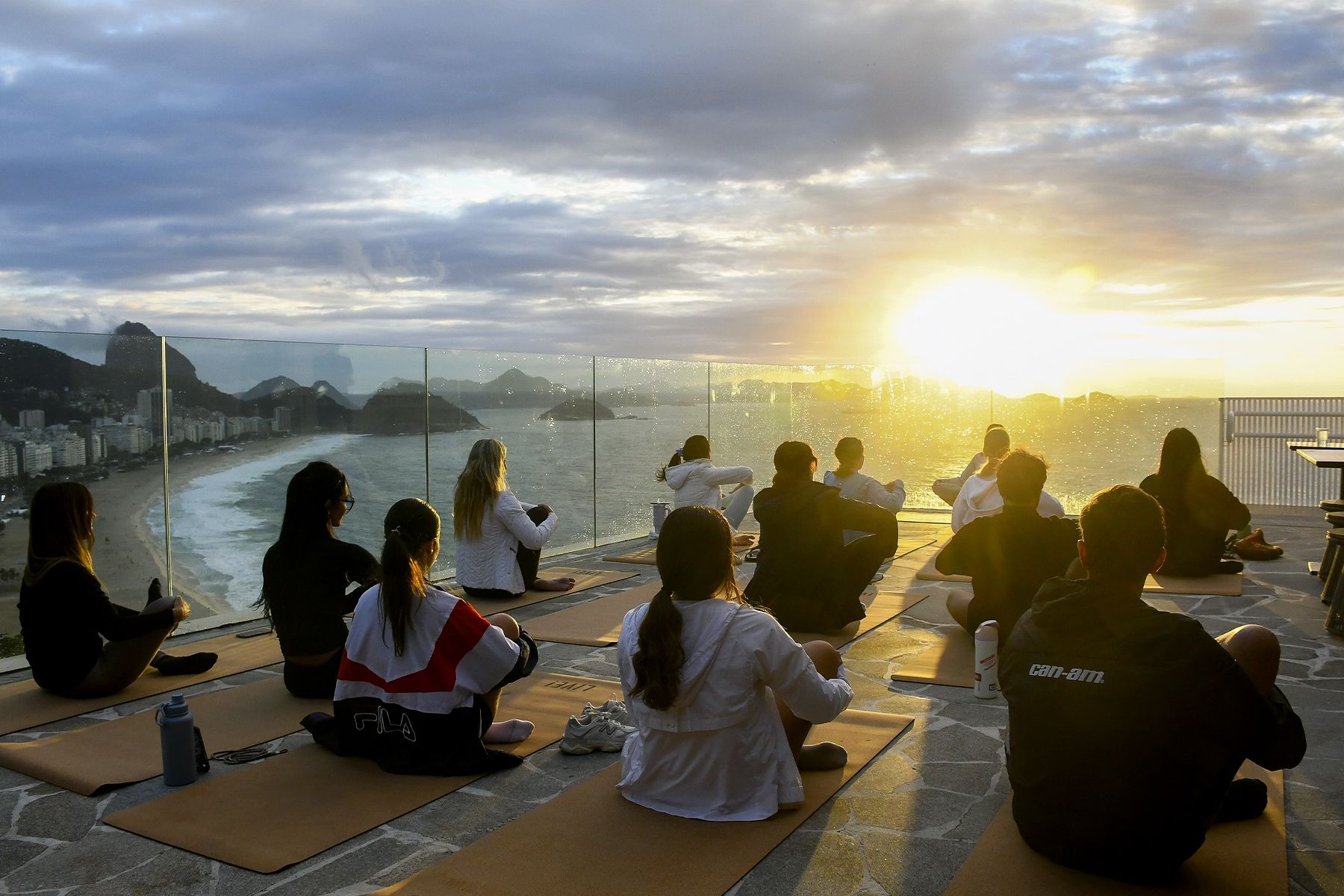 Uma tigela de flores está sobre uma mesa em frente a uma janela com vista para o oceano.