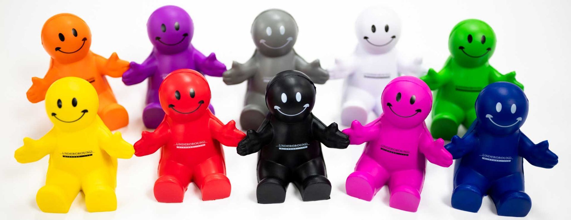 A bunch of colorful smiley faces are sitting next to each other on a white surface.