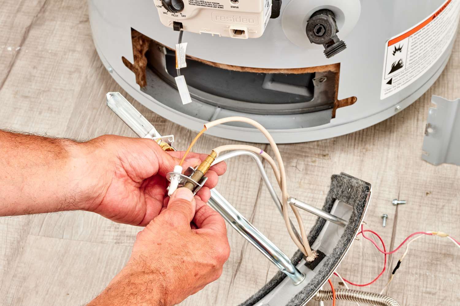 Person replacing a sink drain under a cabinet, with tools and exposed plumbing visible.