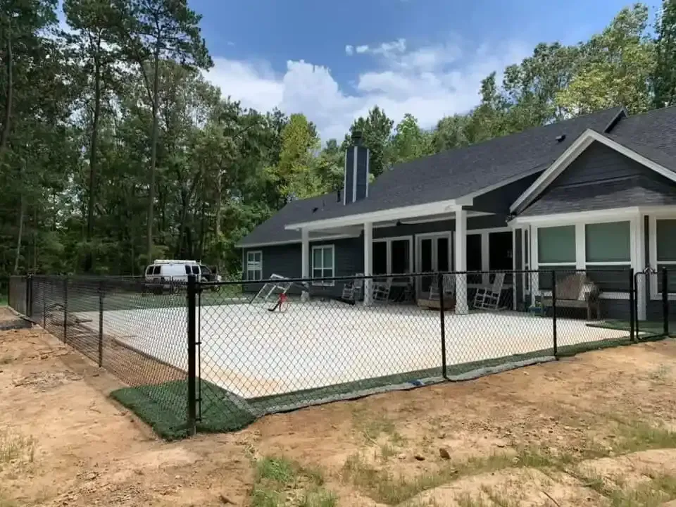 Black chain-link fence surrounds a covered pool by Allen's Tree and Fence.