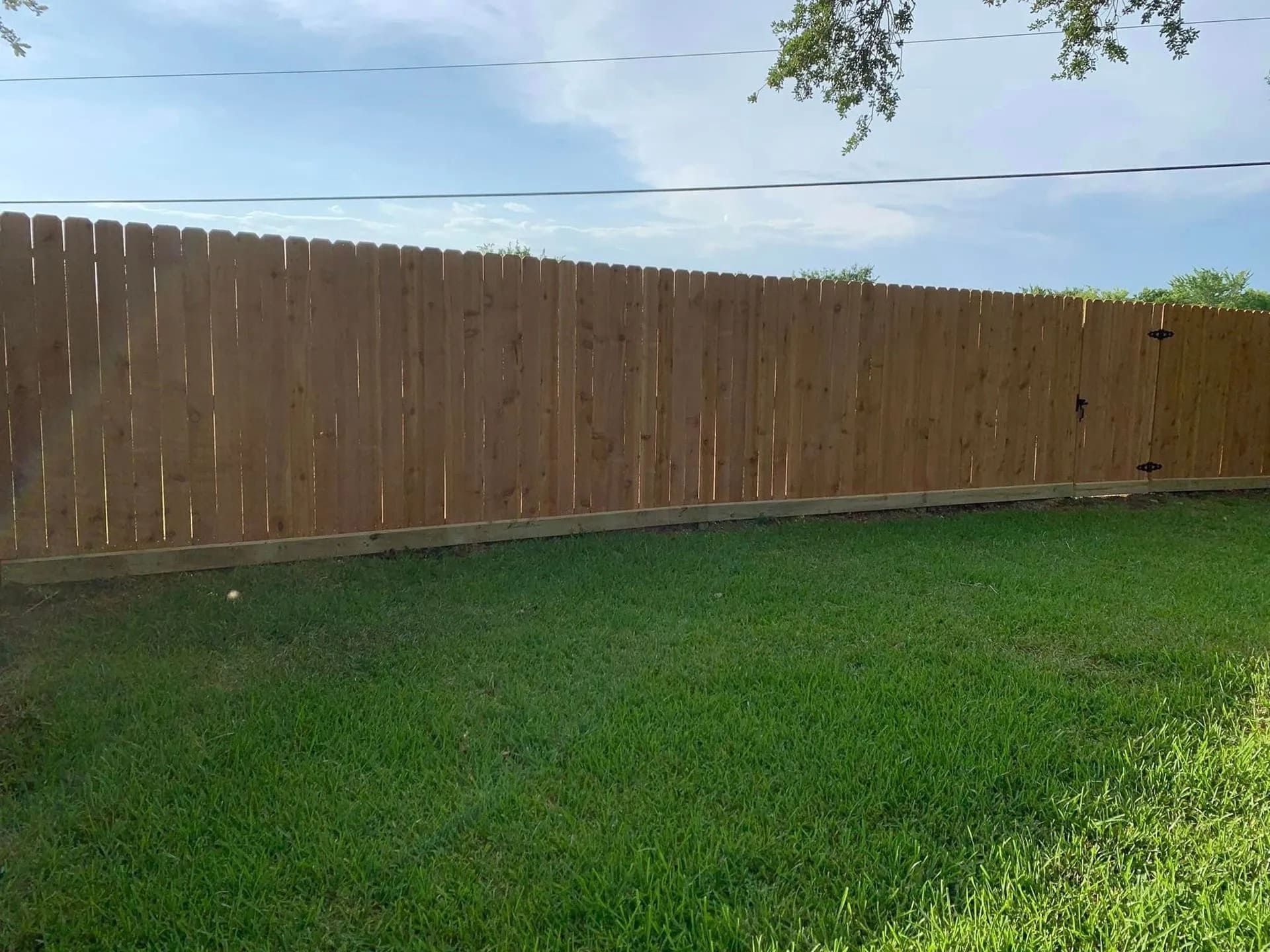 Wooden fence bordering a grassy backyard by Allen's Tree and Fence.