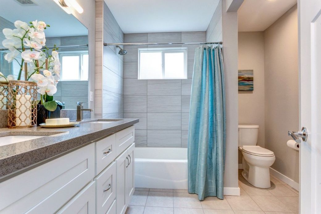 Luxurious white bathroom with marble shower, blue vanity, and gold accents.
