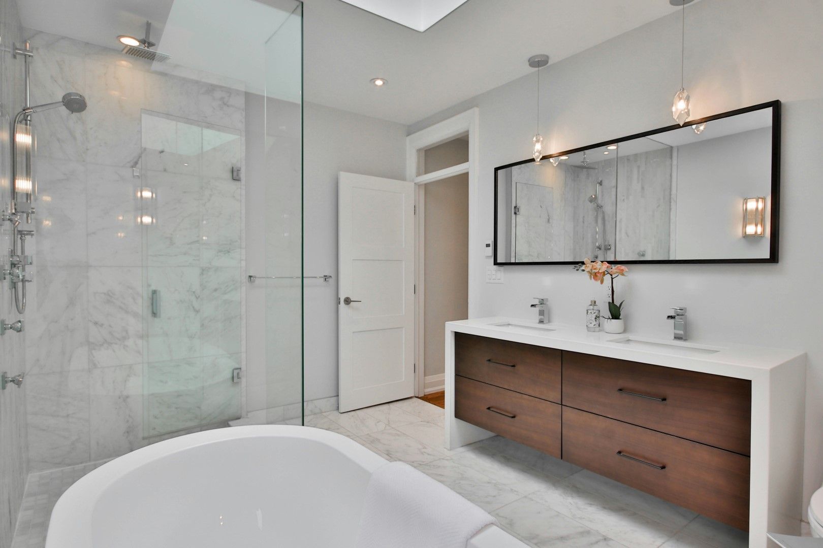 Modern bathroom vanity with wood drawers, wall mirror, and glass shower after kitchen and bathroom remodeling in Avondale, AZ