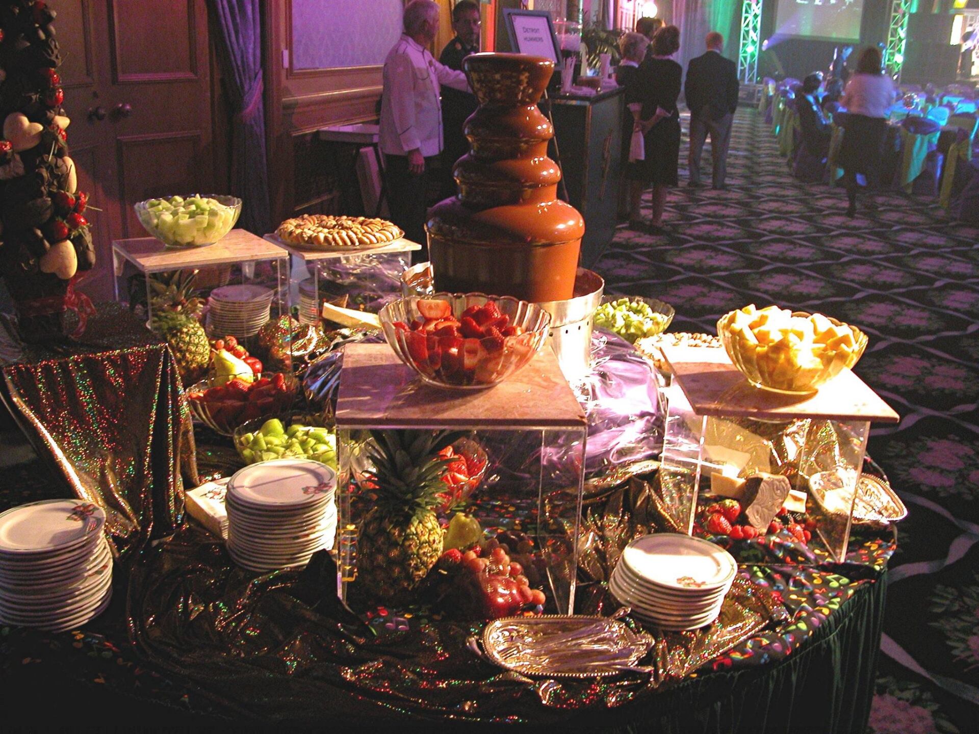 A buffet table with a chocolate fountain in the background
