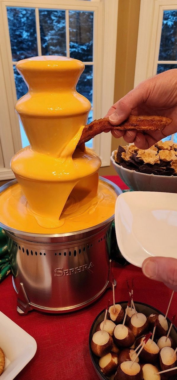A person is dipping a pretzel into a chocolate fountain.