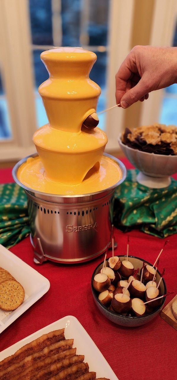 A person is dipping a banana in a chocolate fountain.