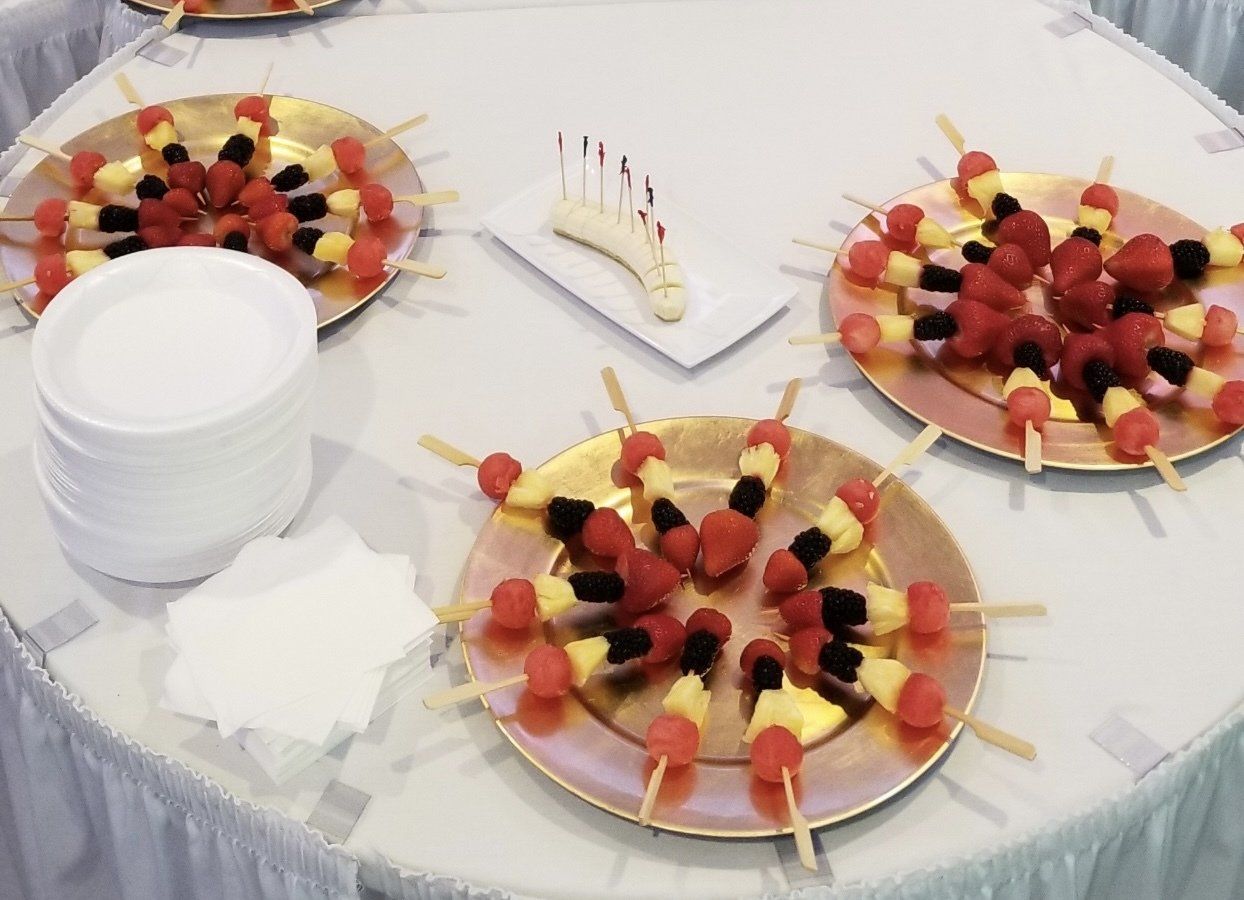 Three plates of fruit on skewers on a table