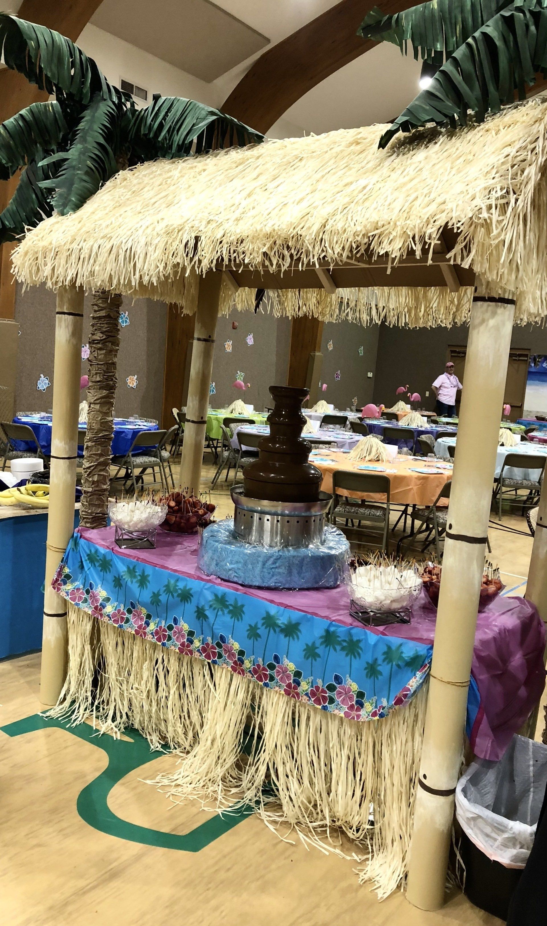 A table with a thatched roof and a chocolate fountain on it.