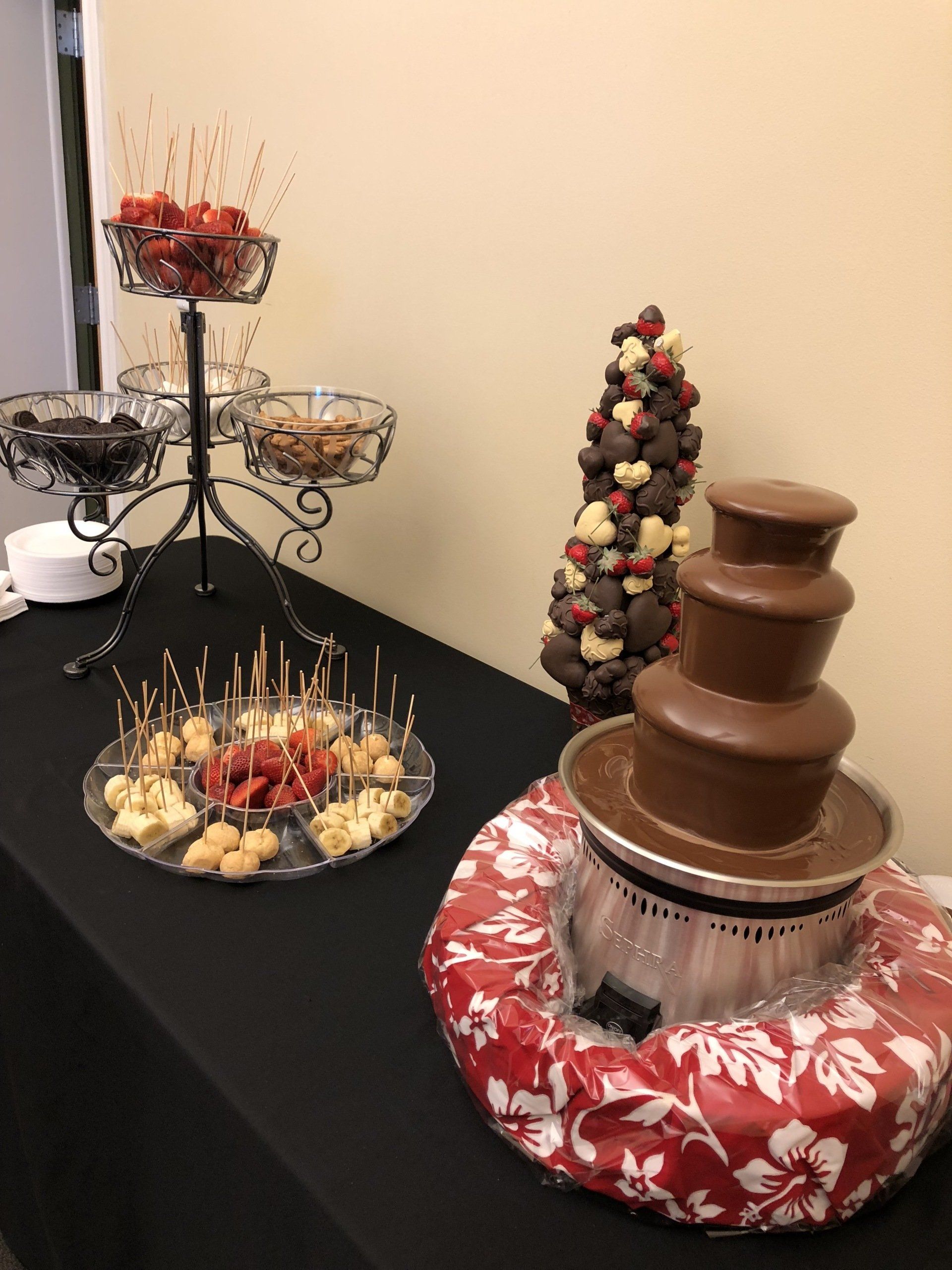 A table with a chocolate fountain and a variety of food on it.
