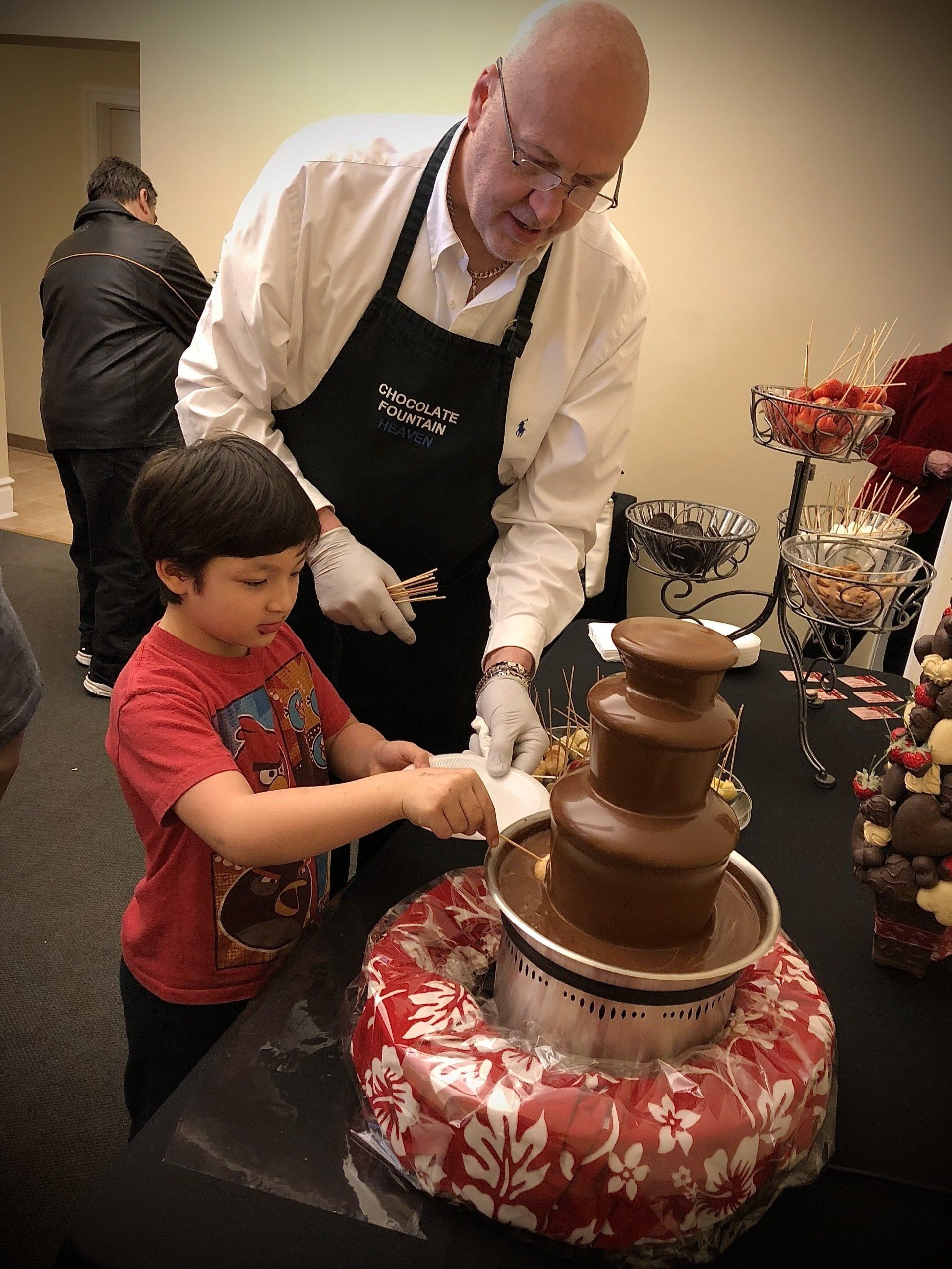 A man and a boy are playing with a chocolate fountain.