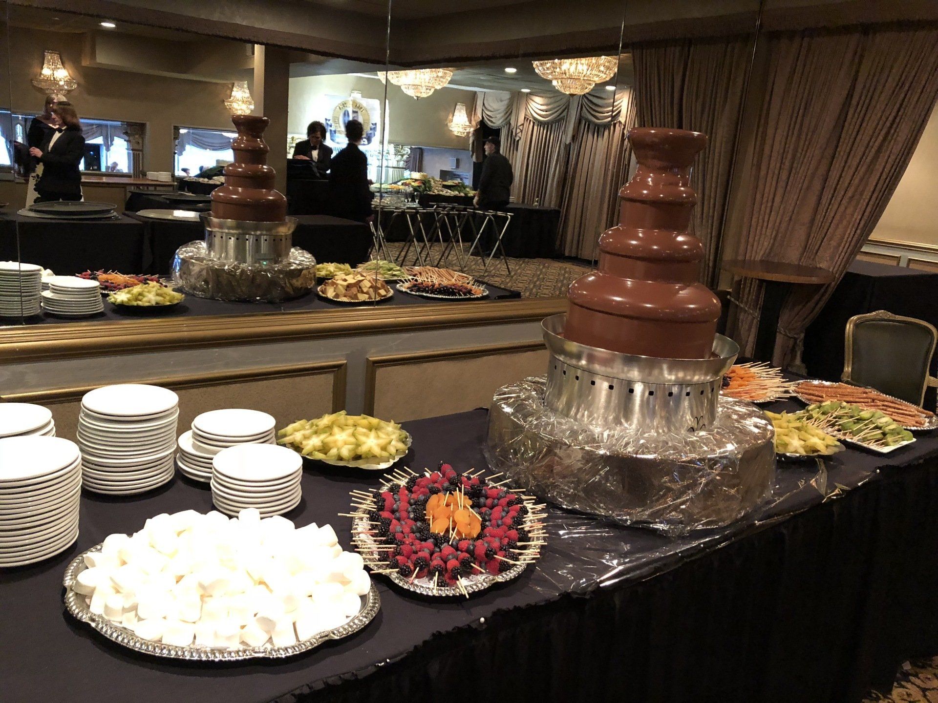 A table with plates of food and a chocolate fountain on it.