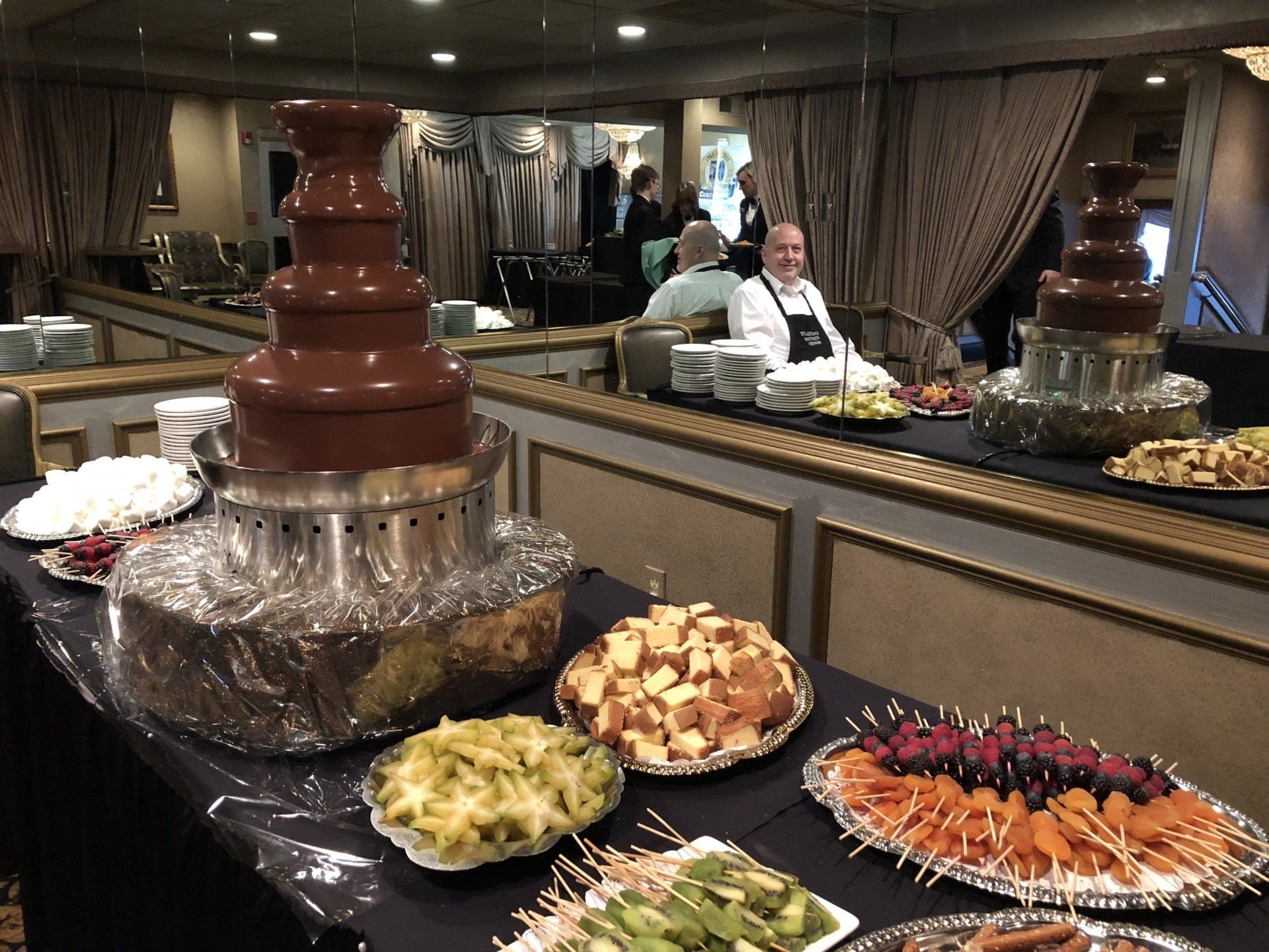 A buffet table with a chocolate fountain in the background